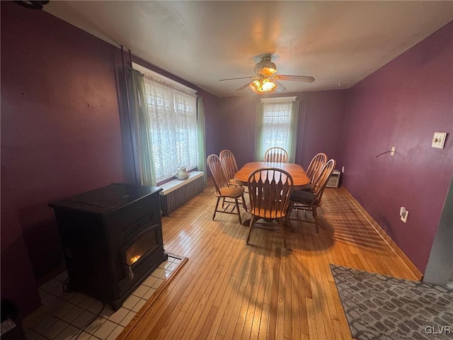 dining room featuring radiator, a wood stove, ceiling fan, and light hardwood / wood-style flooring