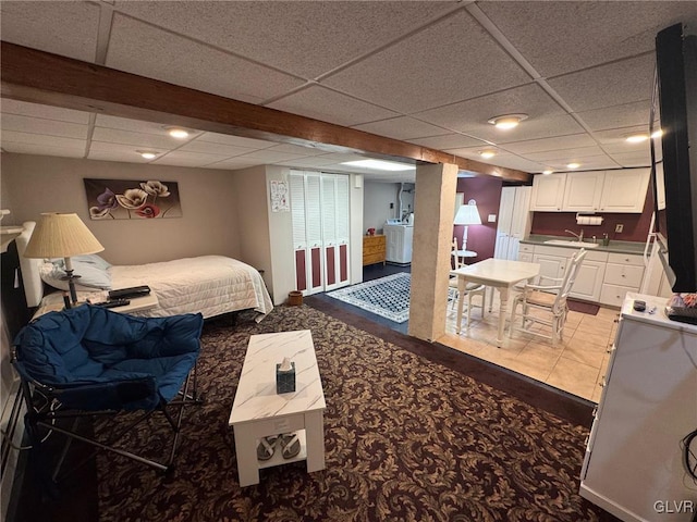 bedroom featuring a drop ceiling, washer / clothes dryer, light carpet, and sink