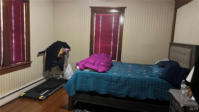 bedroom with hardwood / wood-style flooring and a baseboard heating unit