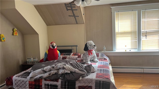 bedroom featuring lofted ceiling, light wood-type flooring, and baseboard heating