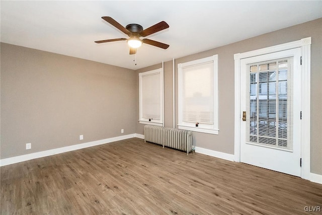 spare room featuring ceiling fan, radiator heating unit, and wood-type flooring