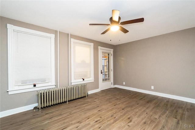 unfurnished room with ceiling fan, radiator heating unit, and wood-type flooring