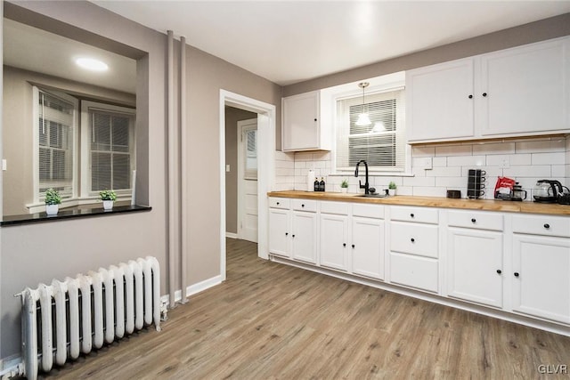 kitchen featuring white cabinetry, wooden counters, light wood-type flooring, radiator, and decorative backsplash