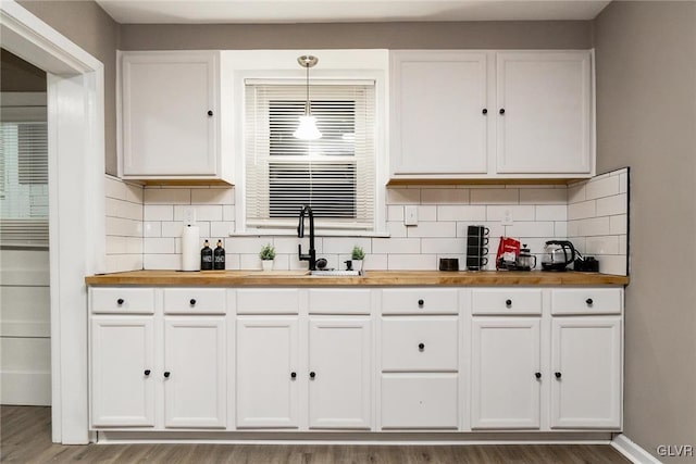 kitchen with white cabinetry, decorative light fixtures, and butcher block counters