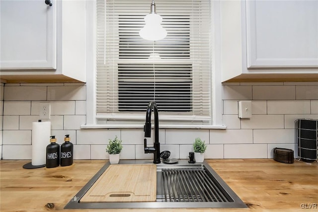 details with white cabinetry, sink, wooden counters, and decorative light fixtures