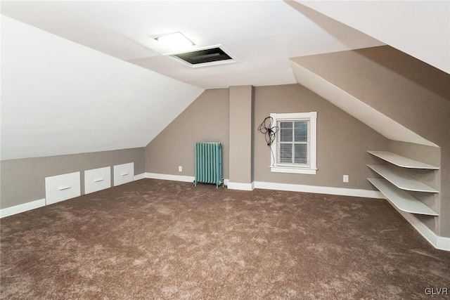 bonus room with dark colored carpet, lofted ceiling, and radiator heating unit