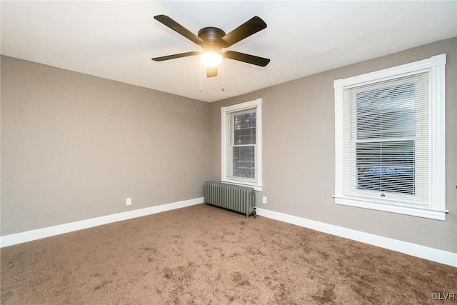 empty room with ceiling fan, radiator, and carpet floors