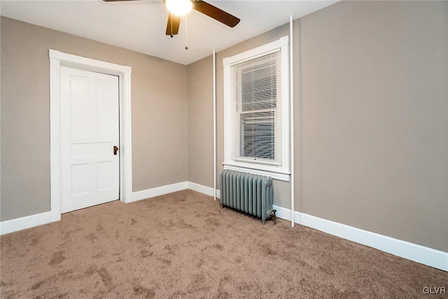 carpeted empty room featuring radiator heating unit and ceiling fan