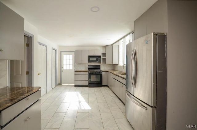 kitchen with white cabinetry, sink, decorative backsplash, and black appliances