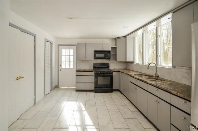 kitchen featuring sink, gray cabinets, tasteful backsplash, black appliances, and dark stone counters