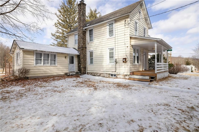 snow covered back of property with a porch