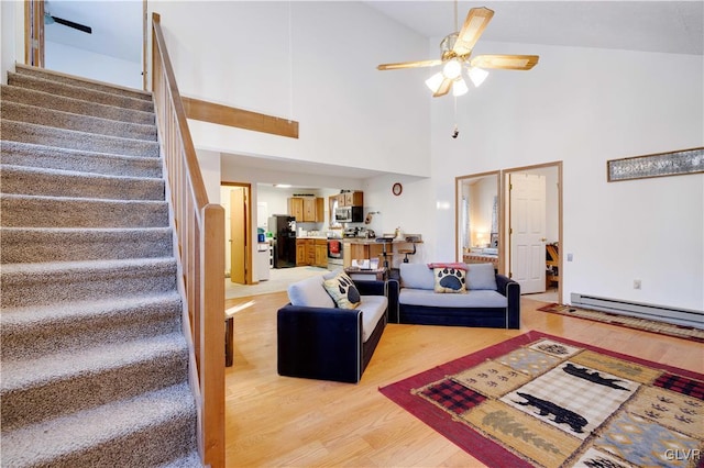 living room featuring light hardwood / wood-style flooring, a baseboard radiator, ceiling fan, and a high ceiling