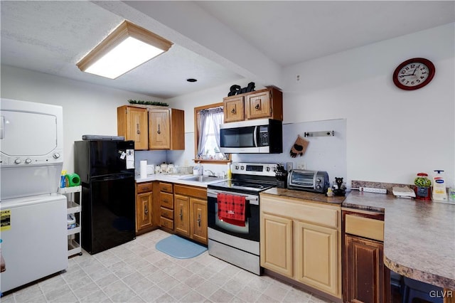 kitchen featuring stacked washer / drying machine, stainless steel appliances, and sink