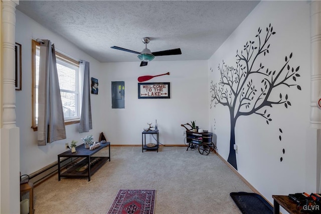 living area with ceiling fan, ornate columns, a textured ceiling, and carpet flooring