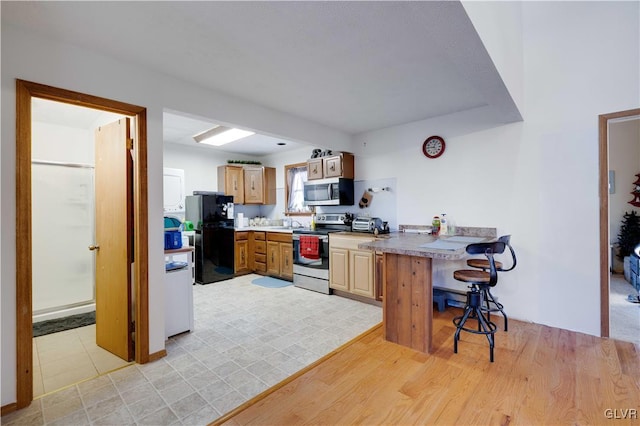 kitchen featuring light wood-type flooring, stainless steel appliances, and a kitchen bar