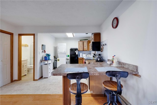 kitchen featuring stove, a kitchen breakfast bar, kitchen peninsula, and light wood-type flooring