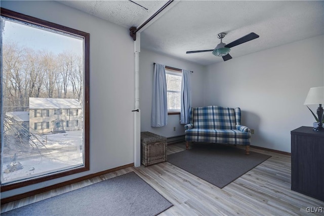 unfurnished room with ceiling fan, a textured ceiling, and light wood-type flooring