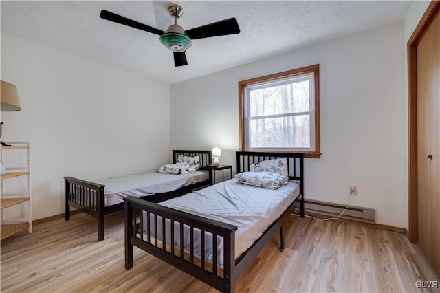 bedroom featuring baseboard heating, ceiling fan, light hardwood / wood-style flooring, and a textured ceiling