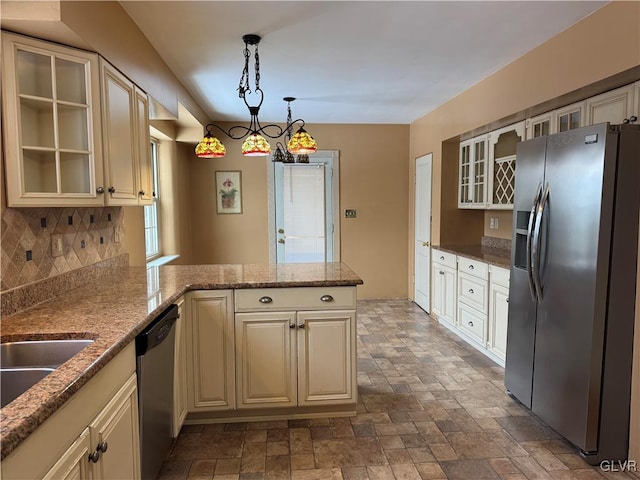 kitchen with appliances with stainless steel finishes, kitchen peninsula, cream cabinetry, and decorative light fixtures