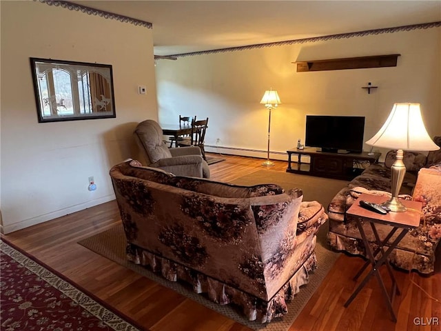 living area with a baseboard radiator, baseboards, and wood finished floors