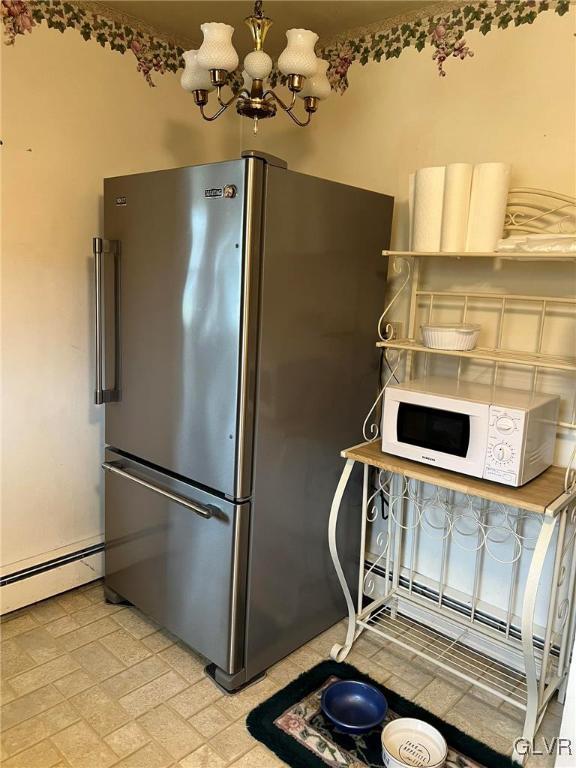 kitchen featuring baseboard heating, stainless steel fridge, and a notable chandelier