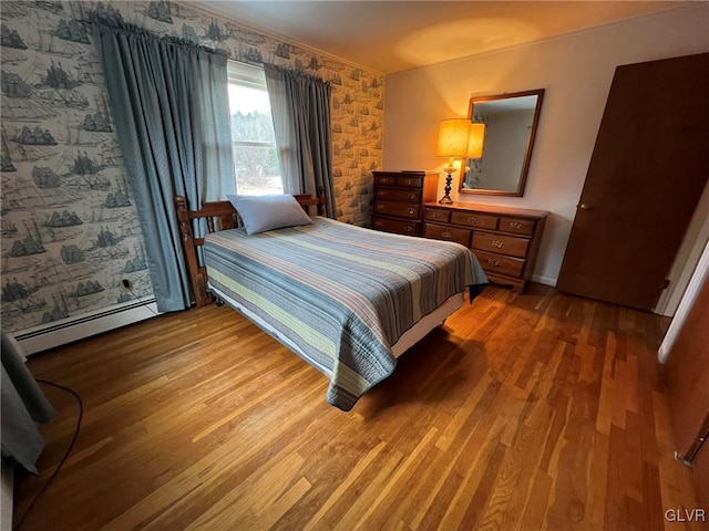 bedroom featuring hardwood / wood-style flooring and a baseboard heating unit