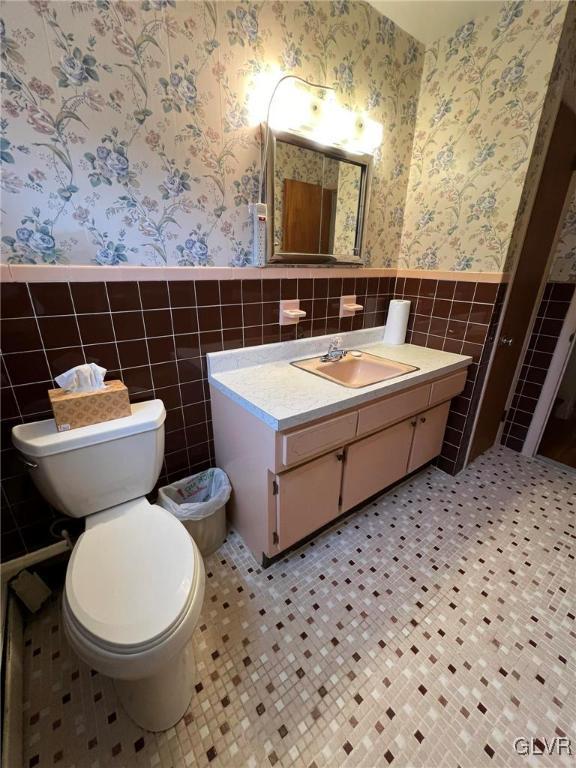 bathroom featuring tile walls, toilet, and vanity