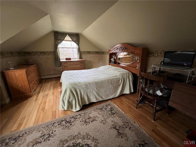 bedroom with light hardwood / wood-style floors, baseboard heating, and vaulted ceiling