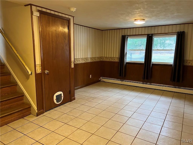 tiled empty room featuring wood walls and a baseboard radiator