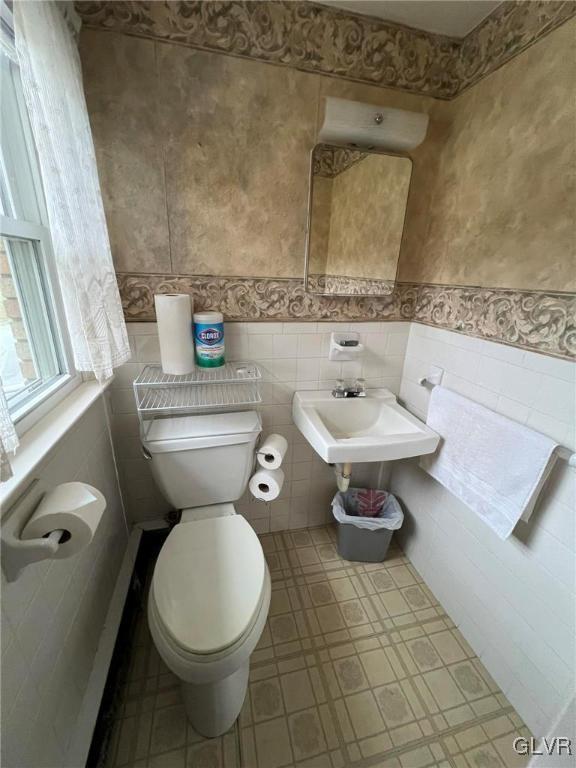 bathroom featuring sink, tile walls, and toilet