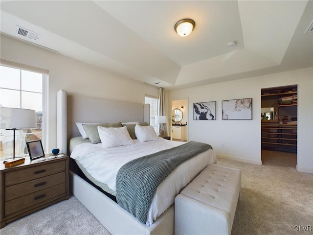 bedroom featuring multiple windows, a raised ceiling, visible vents, and light colored carpet