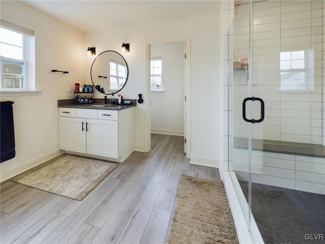 bathroom with wood finished floors, a wealth of natural light, and a shower stall