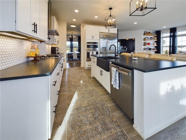 kitchen with white cabinets, dark countertops, appliances with stainless steel finishes, pendant lighting, and a sink