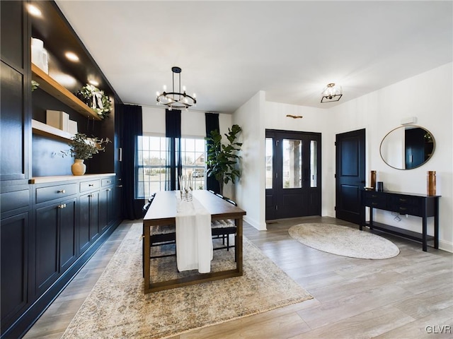 dining area featuring baseboards, light wood finished floors, and a notable chandelier