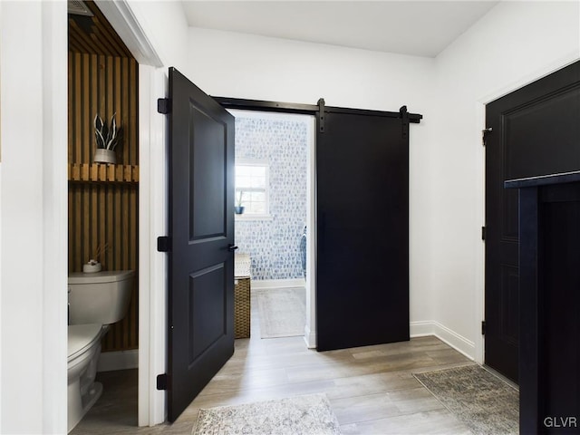 interior space featuring light wood-style flooring, baseboards, and a barn door