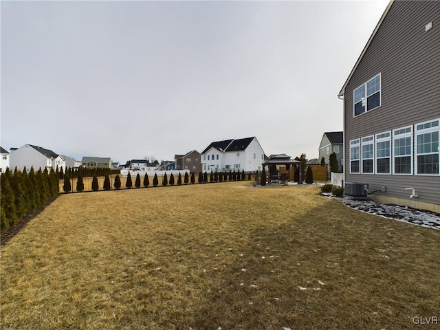 view of yard featuring a residential view, fence, cooling unit, and a gazebo