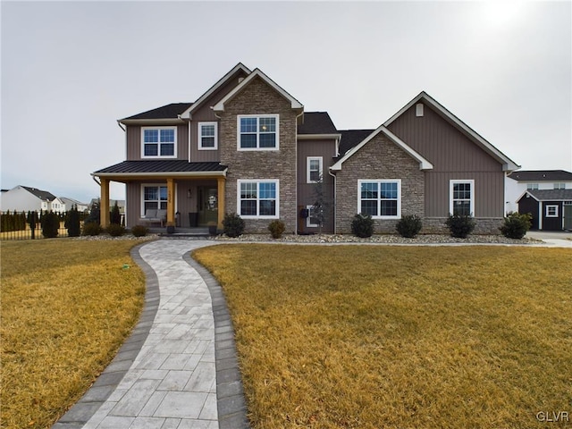 craftsman-style home featuring metal roof, covered porch, stone siding, a standing seam roof, and a front yard