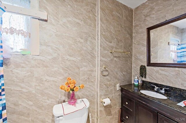 bathroom with tile walls, vanity, and toilet