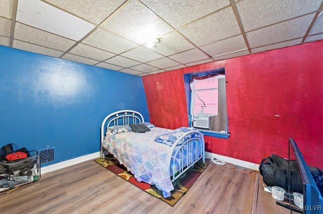 bedroom featuring wood-type flooring, cooling unit, and a drop ceiling