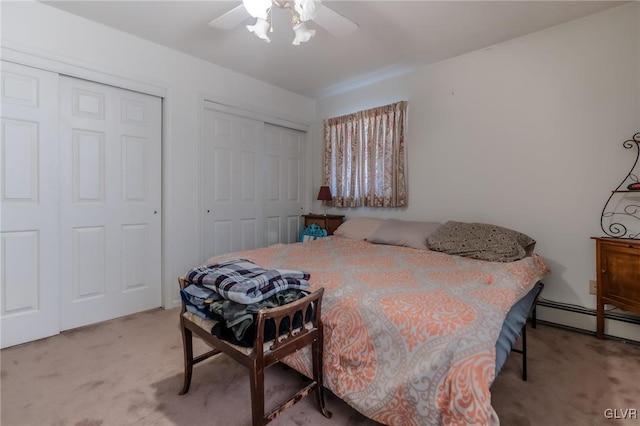 carpeted bedroom featuring two closets, ceiling fan, and baseboard heating