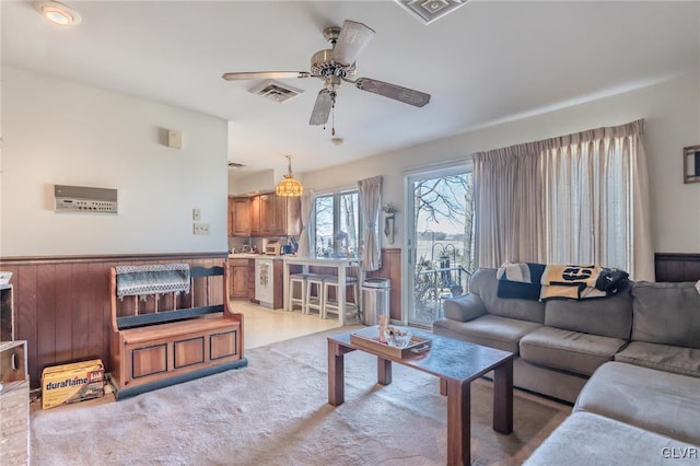 living room with ceiling fan, light colored carpet, and wooden walls