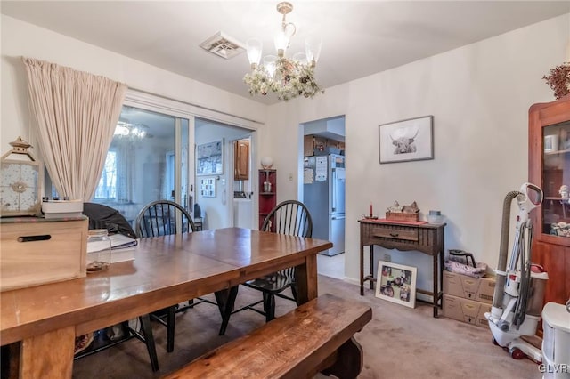 carpeted dining space with a chandelier