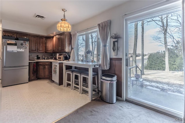 kitchen with dark brown cabinetry, stainless steel refrigerator, and decorative light fixtures