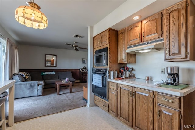 kitchen featuring light carpet, hanging light fixtures, black oven, and ceiling fan