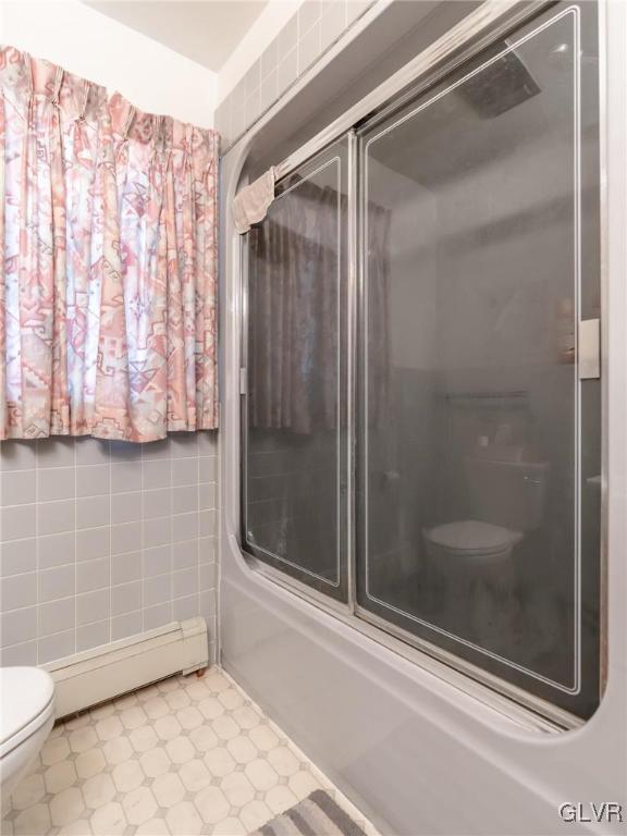 bathroom featuring a baseboard radiator, toilet, and combined bath / shower with glass door