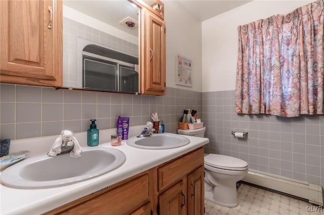 bathroom with baseboard heating, vanity, toilet, and tile walls