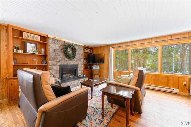 living room with wood ceiling, a baseboard heating unit, wood walls, a fireplace, and light wood-type flooring