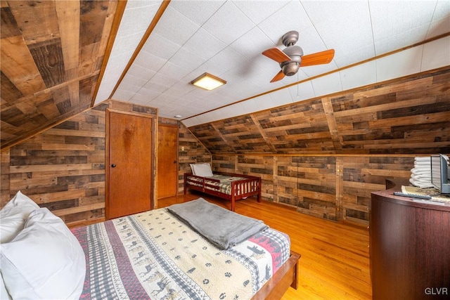 bedroom with lofted ceiling, light hardwood / wood-style flooring, and wood walls