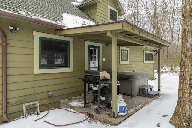 snow covered patio featuring area for grilling and a hot tub