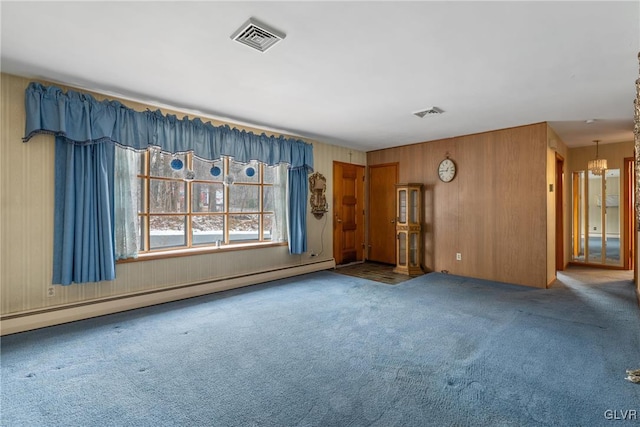 carpeted empty room with a notable chandelier and a baseboard heating unit